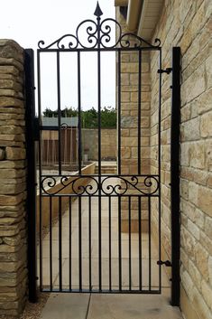 an iron gate on the side of a brick building with a stone wall behind it