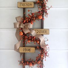 a wreath is hanging on the wall with two wooden signs that say friends and gather here