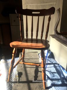 a wooden chair sitting on top of a bed next to a dresser and window sill