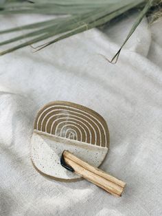 a bowl with a wooden spoon on top of it next to a plant and white cloth