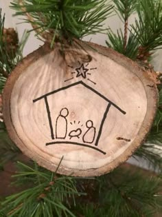 a wooden ornament with a house drawn on it's side hanging from a christmas tree