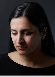 a woman is looking down at her cell phone while wearing a black shirt and earrings