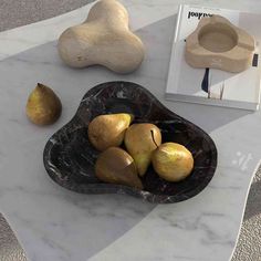 a marble table topped with pears next to a book and other items on top of it