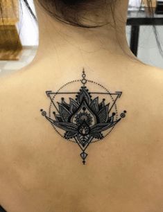 the back of a woman's neck with an intricate tattoo design on her left shoulder