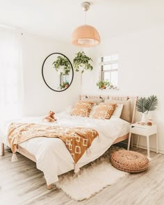 a bedroom with white walls and wooden flooring is decorated in neutral colors, including an orange bed spread