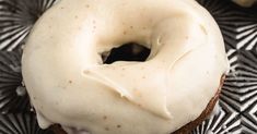 a frosted donut sitting on top of a black and white plate with silver designs