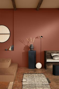 a living room with red walls and brown tile flooring, two round mirrors on the wall