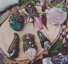 several pieces of jewelry sitting on top of a piece of wood next to some rocks