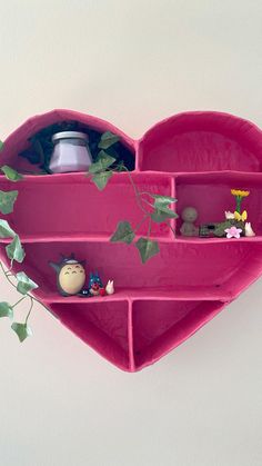 a pink heart shaped shelf with various items on it