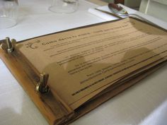 a menu sitting on top of a wooden cutting board next to a knife and fork