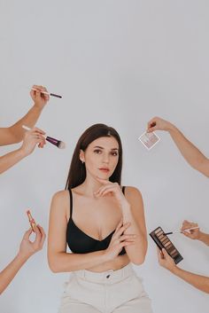 a woman standing in front of makeup brushes and other women holding their hands up to her face