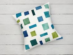 a white pillow with green and blue squares on it