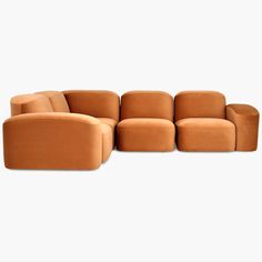 an orange couch sitting on top of a white floor next to a chair and ottoman