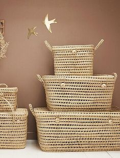 several baskets stacked on top of each other in front of a wall with birds flying above them