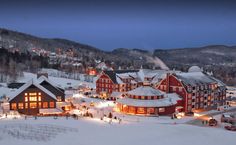 a ski resort at night with snow on the ground and lit up buildings in the background