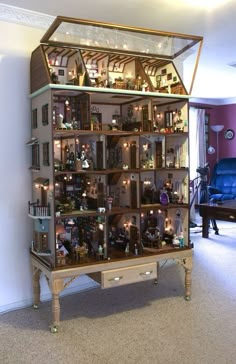 a doll house with lots of furniture and lights in the middle of it's display case