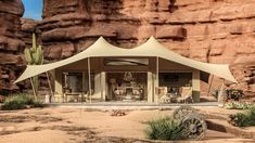 a tent set up in the desert with rocks and cactus