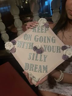 a woman holding up a sign that says keep on going with your silly dream in it