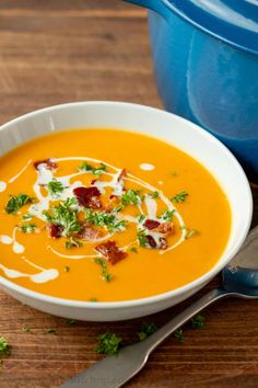 a bowl of carrot soup with bacon and sour cream