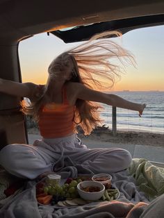 a woman sitting in the back of a van with her arms outstretched and legs spread out