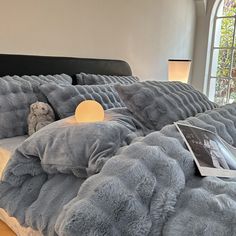 a teddy bear is sitting on the bed with pillows and blankets in front of it