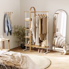 a bedroom with clothes hanging on racks and a mirror in the corner next to it