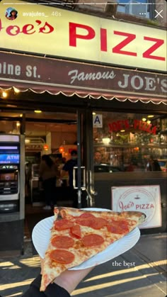 a slice of pepperoni pizza on a paper plate in front of a storefront