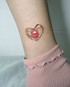 a woman's leg with a heart shaped tattoo on her left ankle, and a candy in the shape of a heart