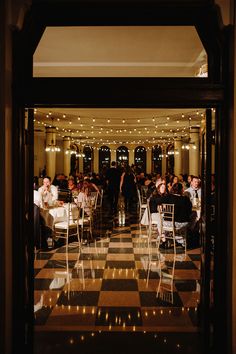 people sitting at tables in a restaurant with black and white checkerboard flooring