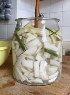 a jar filled with sliced up vegetables on top of a wooden table