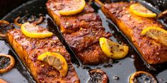 three pieces of meat with lemons and mushrooms on top of it in a pan