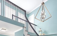 a chandelier hanging from the ceiling in a room with blue walls and stairs