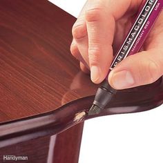 a person is writing on a piece of wood with a marker in their left hand