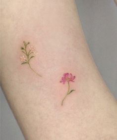 two small pink flowers on the side of a woman's leg, one with green stems