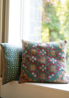 two pillows sitting on top of a window sill