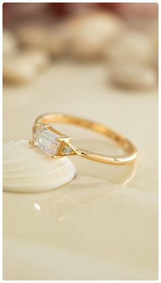 a close up of a gold ring with a diamond on the side and a seashell