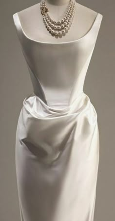 a mannequin with a white dress and pearls on it's neckline