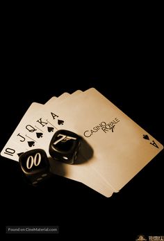 two black dices sitting next to each other on top of playing cards in the dark