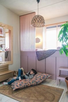 a woman laying on top of a bed next to a potted plant in a living room