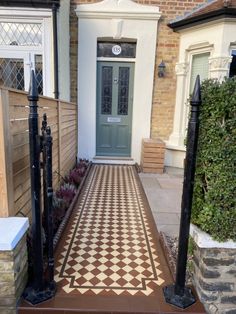 a house with a checkered tile walkway leading to the front door