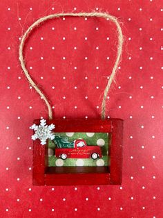 an ornament hanging from a string on top of a red surface with white dots