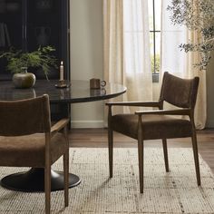 two chairs sitting in front of a table with a vase on top of it next to a window