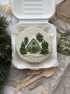 a cake decorated like a house on top of a paper plate in a foam container