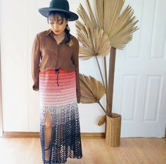 a woman standing in front of a plant wearing a hat