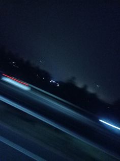 blurry photograph of street lights at night with trees in the background and dark sky
