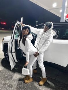 two people standing next to a white car