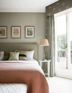 a bed sitting in a bedroom next to a window with pictures on the wall above it