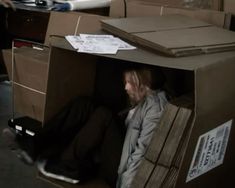 a man is sitting in a cardboard box