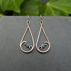 the earrings are made with copper wire and blue glass beaded beads, on top of a slate slab