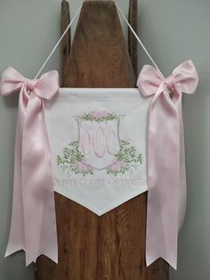 a wooden chair with a pink ribbon hanging from it's back and the name jocc on it